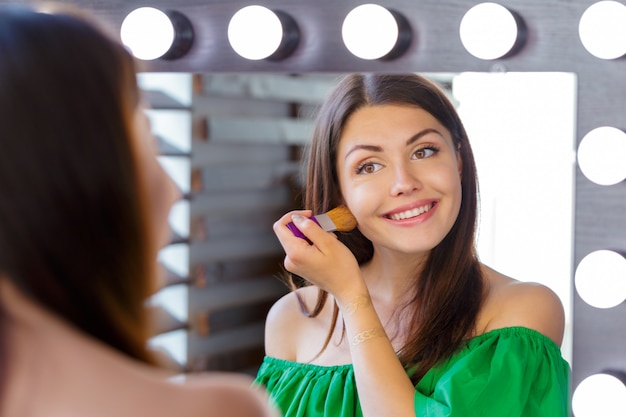 Mujer morena aplicando maquillaje para una cita nocturna