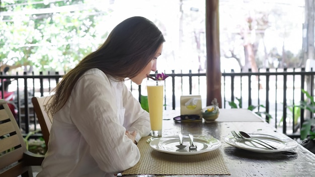 Mujer morena bebe batido en la vista lateral de la cafetería