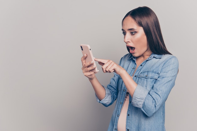 Mujer morena con chaqueta de jeans sosteniendo su teléfono