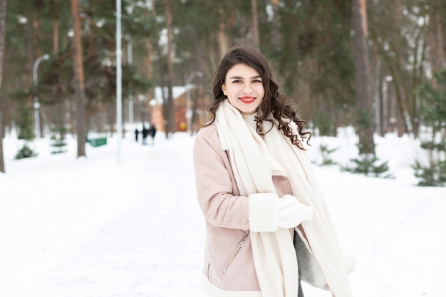 Mujer morena complacida caminando en el bosque en invierno. Espacio para texto