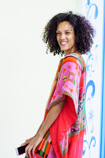 Mujer morena delgada sonriendo con cabello afro, estilo libre de fondo blanco