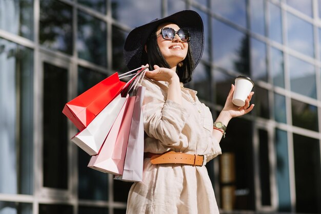 Mujer morena feliz sosteniendo bolsas de compras al aire libre. Mujer adicta a las compras satisfecha con las compras.