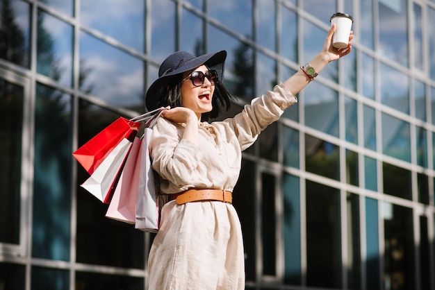 Mujer morena feliz sosteniendo bolsas de compras al aire libre. Mujer adicta a las compras satisfecha con las compras.