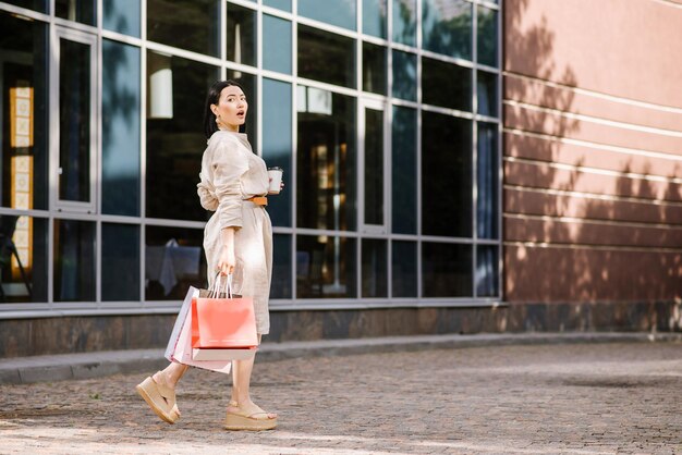 Mujer morena feliz sosteniendo bolsas de compras al aire libre. Mujer adicta a las compras satisfecha con las compras.