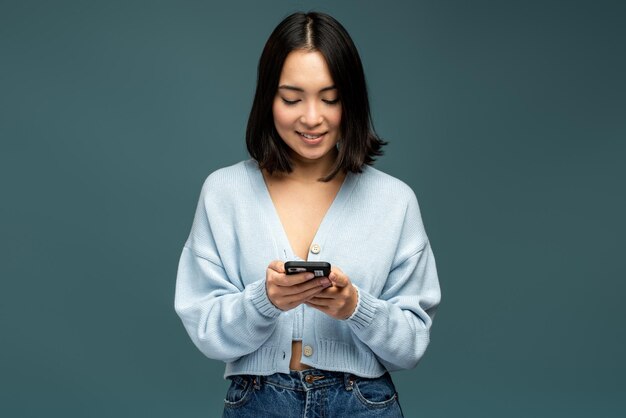 Mujer morena feliz usando teléfono móvil y sonriendo alegremente, mientras escribe o lee mensajes divertidos en las redes sociales. Concepto de comunicación en línea