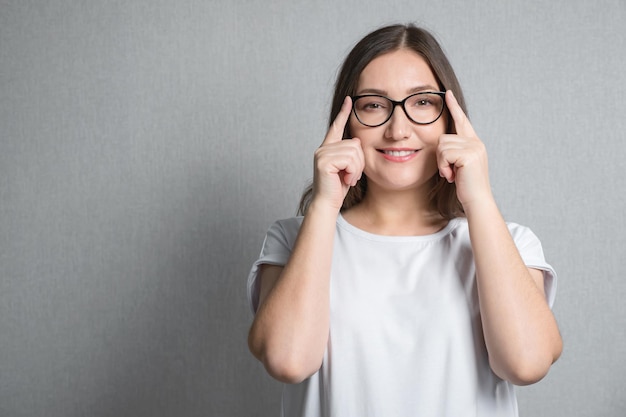 Mujer morena con gafas con las dos manos en el puente de la nariz