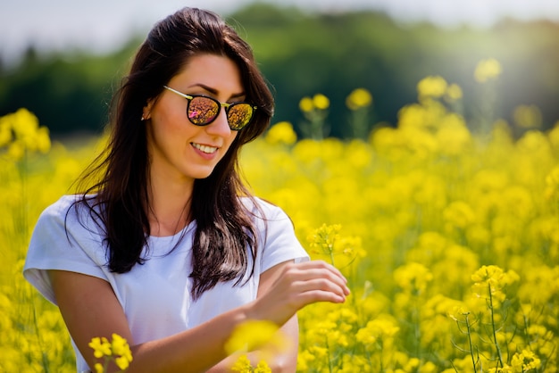 Mujer morena con gafas de sol en medio del campo floreciente