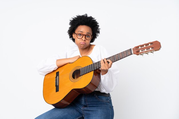 Mujer morena con una guitarra sobre fondo blanco.