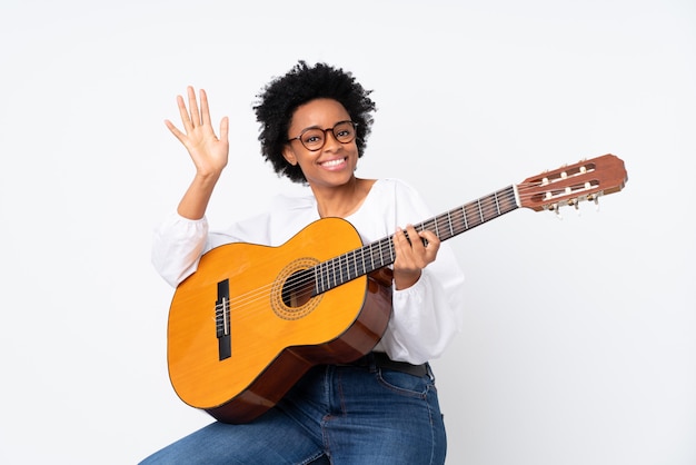 Mujer morena con una guitarra sobre fondo blanco.