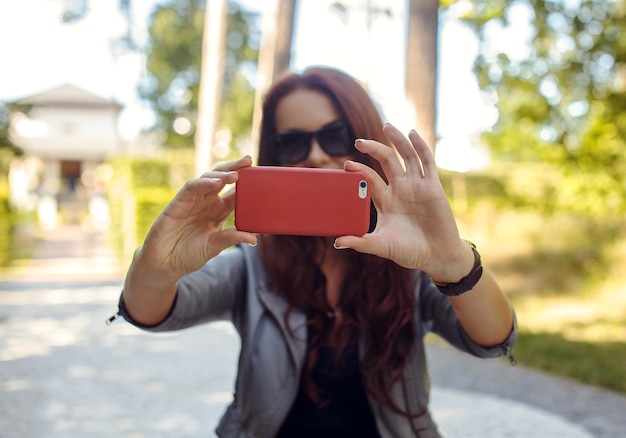 Mujer morena haciendo fotos en un smartphone rosa.