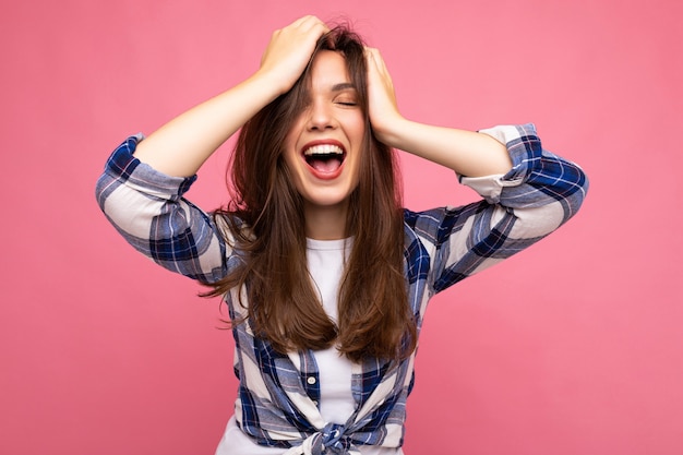 Mujer morena hermosa joven. Señora de moda en camisa casual de verano hipster. La mujer positiva muestra emociones faciales sinceras. Modelo divertido aislado sobre fondo rosa con espacio libre.