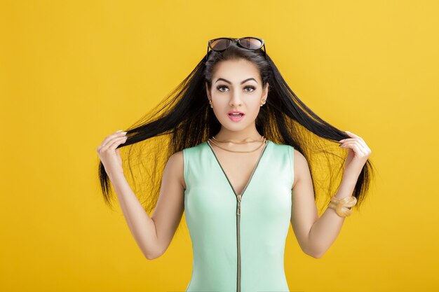 Mujer morena joven atractiva en un traje de baño verde sobre un amarillo. mujer sorprendida en un traje turquesa