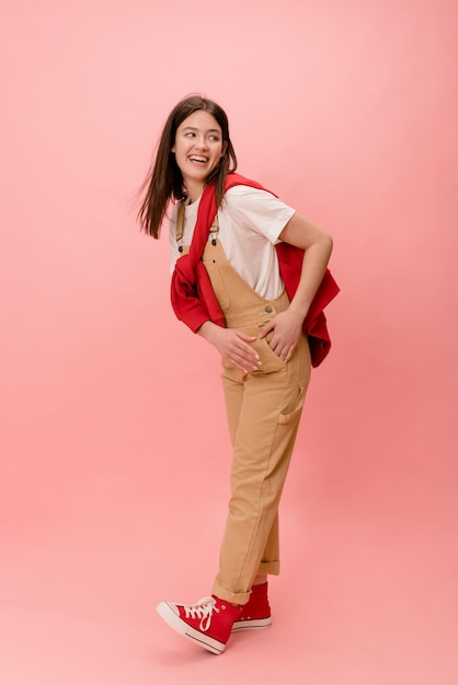 Mujer morena joven caucásica de moda de longitud completa viste ropa casual mirando hacia otro lado sobre fondo rosa Gente emociones sinceras concepto de estilo de vida