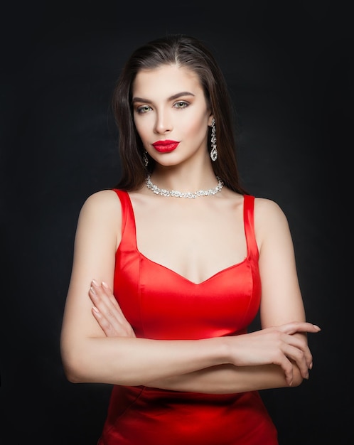 Mujer morena joven con maquillaje de labios rojos y collar de diamantes y aretes retrato