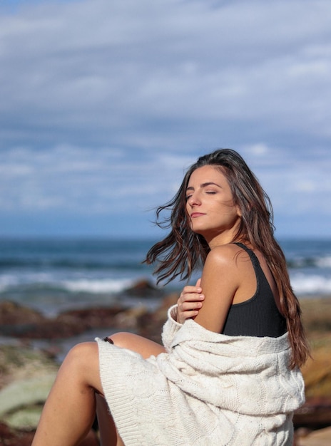 Mujer morena joven que siente la brisa del mar en su cara y cabello en la playa