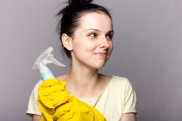 mujer morena limpiadora con guantes amarillos sosteniendo esponja para lavar platos y limpiador de ventanas