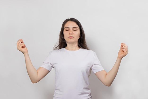 Mujer morena medita en blanco y toma las manos en estilo zen.