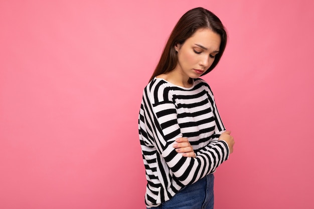 Foto mujer morena molesta triste bastante joven atractiva linda que desgasta la manga larga a rayas ocasional aislada sobre fondo colorido con el espacio de la copia.