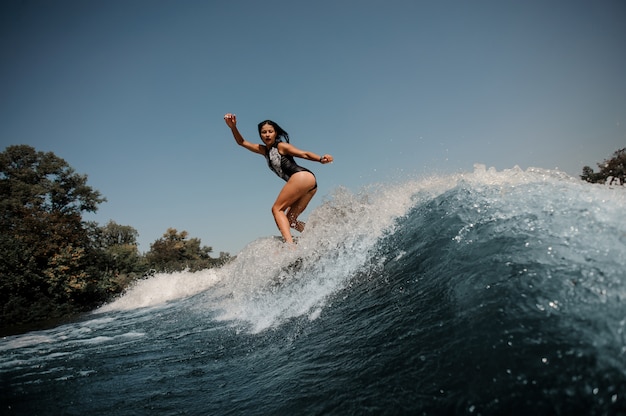 Mujer morena navega en tabla de surf en el mar