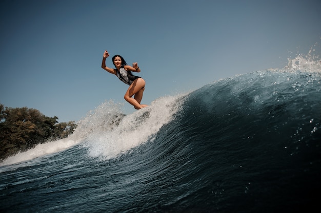 Mujer morena navegando en una tabla de surf en el mar