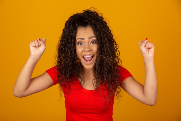 Mujer morena con pelo largo y brillante rizado celebrando