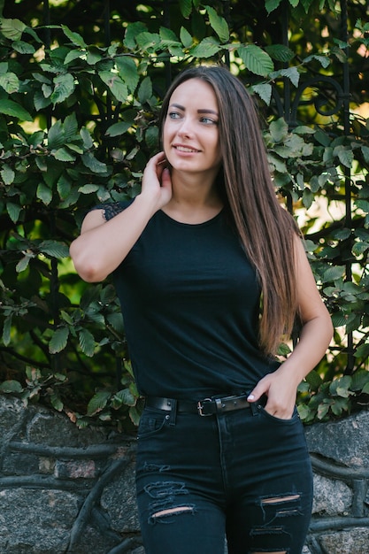 Una mujer morena con el pelo largo con una camiseta negra en blanco