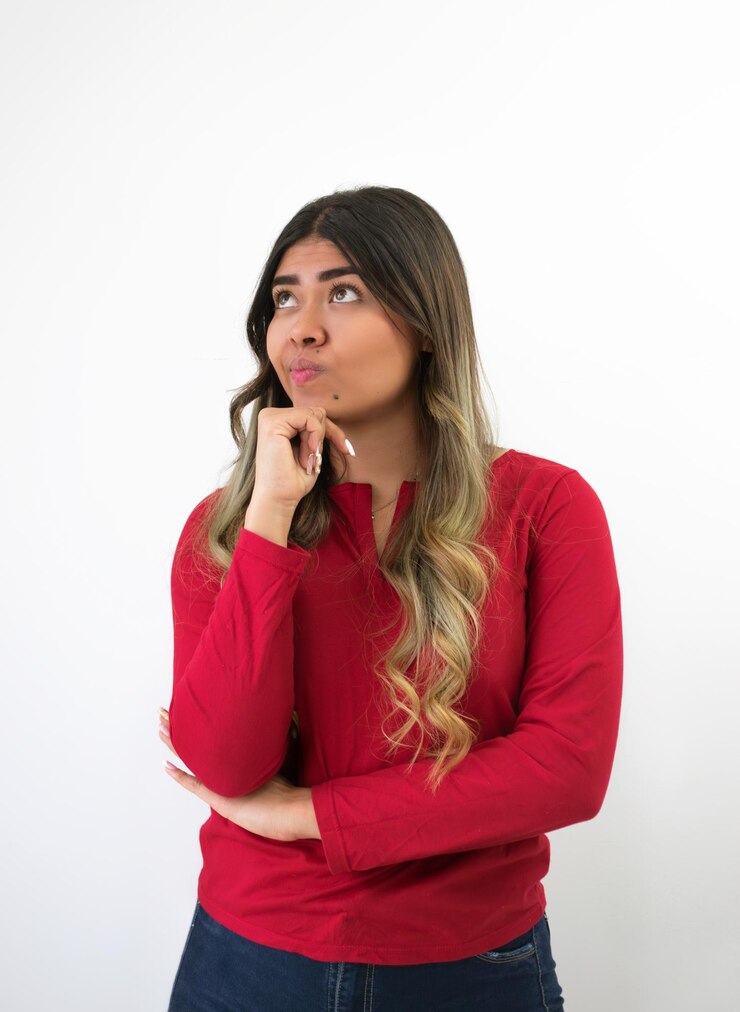 Foto una mujer morena pensativa mirando hacia arriba con una camiseta roja