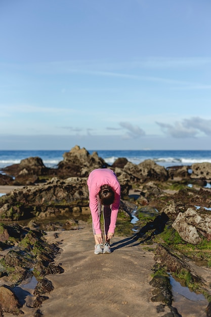 Mujer morena practicando yoga en la playa