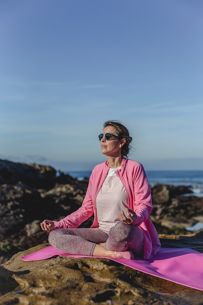 Mujer morena practicando yoga en la playa