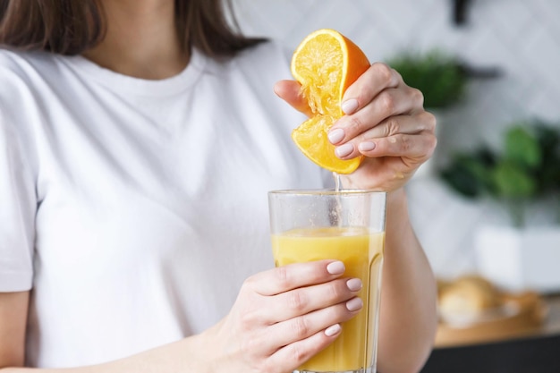 Mujer morena preparando naranja fresca en la cocina ligera