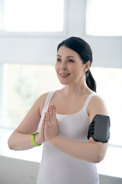 Mujer morena realizando namaste, presionando las manos juntas, usando un pulsómetro