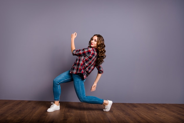 Mujer morena en ropa casual posando contra la pared púrpura