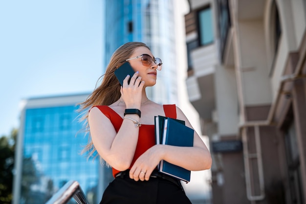 Una mujer morena con ropa de marca pide un taxi a través de una aplicación para smartphones El concepto de una mujer fuerte