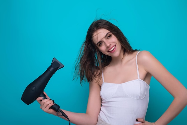 Foto mujer morena con secador de cabello en el fondo del estudio cabellos estilo y concepto de belleza chica hermosa