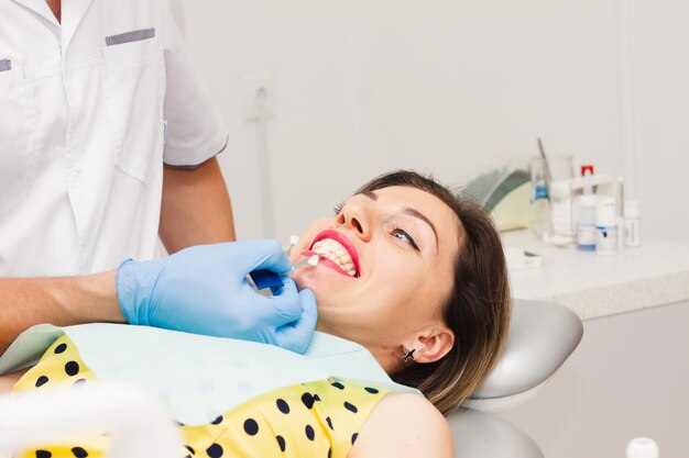 Una mujer morena sentada en el procedimiento del dentista.