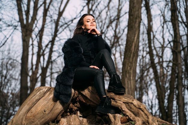 Mujer morena sentada sobre una roca en el parque