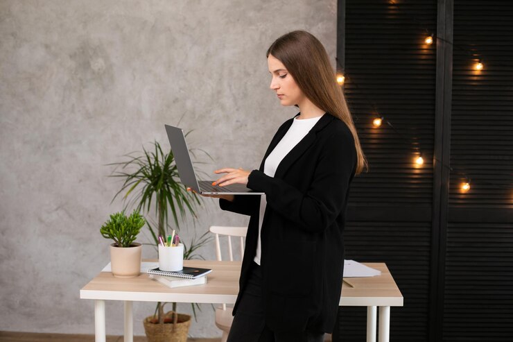 mujer morena seria usando computadora portátil sobre fondo gris. Mujer trabajadora.