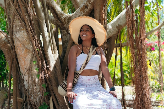 Mujer morena con sombrero posando al aire libre