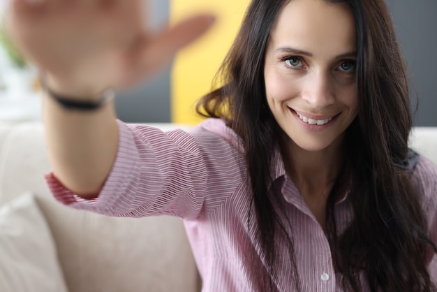 Foto mujer morena sonríe y saluda con su mano