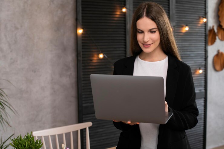 Mujer morena sonriente usando computadora portátil sobre fondo gris