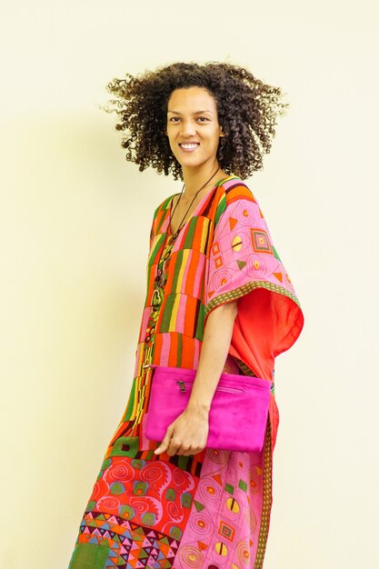 Mujer morena sonriente vistiendo ropas tradicionales con fondo blanco.