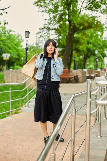 Mujer morena sosteniendo bolsas de papel y hablando por teléfono