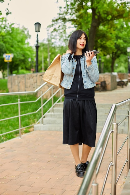 Mujer morena sosteniendo bolsas de papel y hablando por teléfono