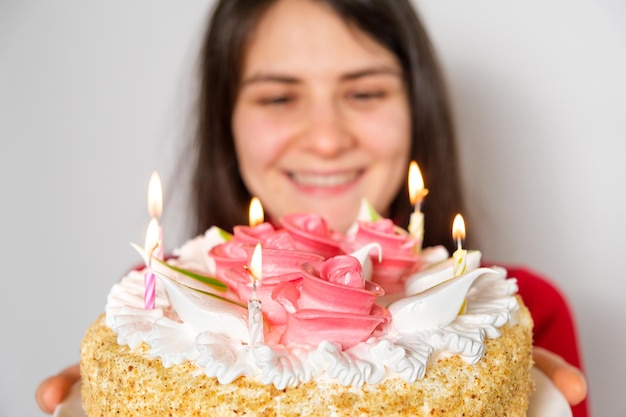 Una mujer morena sostiene un gran pastel blanco.