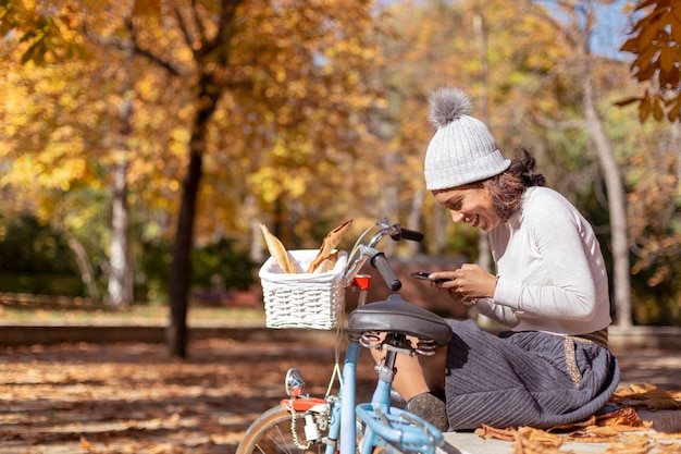 Mujer morena con su teléfono móvil en el parque.