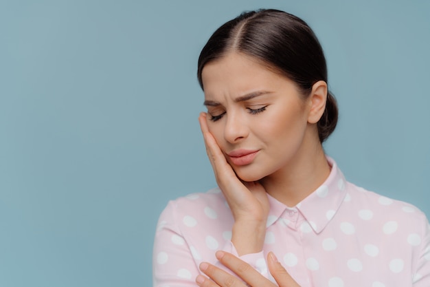 La mujer morena sufre un terrible dolor de dientes fuerte