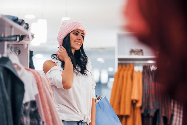 Foto mujer morena en el supermercado tiene día de compras y con sombrero.