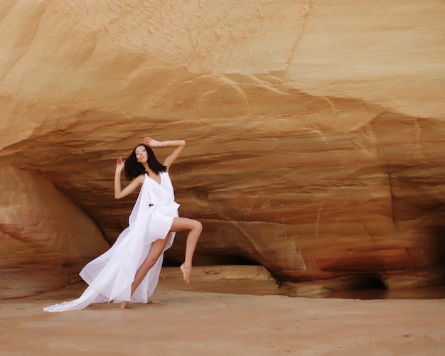 Mujer morena con vestido blanco bailando en el desierto