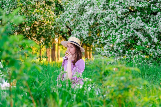 Una mujer morena con un vestido morado posa en un picnic con una copa de vino blanco en el parque en primavera