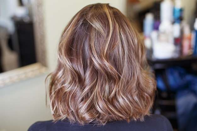 Mujer morena con vista posterior de cabello rizado marrón brillante en el salón